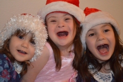 child-with-Down-Syndrome-in-center-with-sisters-on-either-side