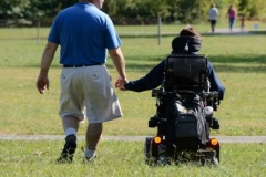 dad-and-daughter-with-spina-bifida-in-wheelchair-holding-hands-strolling-across-field