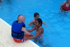 two-children-with-Down-Syndrome-playing-in-pool-with-friend