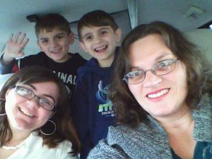 Mom and 3 kids in a minivan smiling