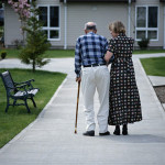 Woman walking down sidewalk with elderly man with cane